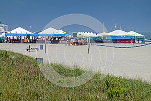 Many colorful large tents and a crowd of people on the beach near the ocean