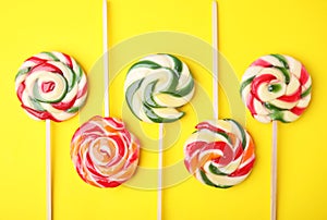 Many colorful lollipops on yellow background, flat lay