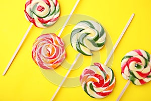 Many colorful lollipops on yellow background, flat lay