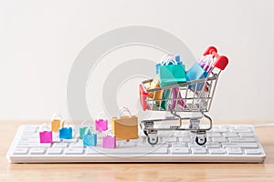 many colorful miniature shopping bags in cart with computer keyboard, online shopping concept