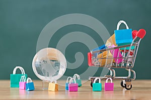 Many colorful miniature shopping bags in cart and globe, online