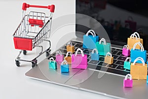 Many colorful miniature shopping bags on laptop, online shopping