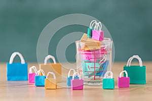 Many colorful miniature shopping bags in measuring cup