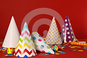 Many colorful party hats and festive items on red background
