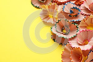 Many colorful pencil shavings on yellow background, closeup. Space for text