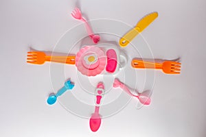 Many colorful plasic forks, spoons and knives on white background with copy space, top view. Devices for baby food
