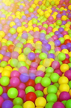 Many colorful plastic balls in a kids& x27; ballpit at a playground.