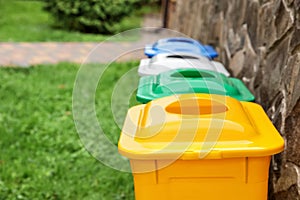 Many colorful recycling bins near stone wall outdoors, closeup. Space for text