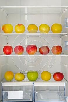 Many colorful ripe apples on the shelf in the fridge. Health starvation, lose weight. Raw diet, starving concept