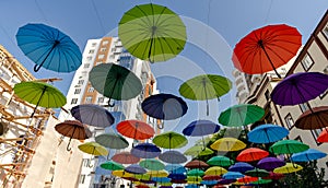 many colorful umbrellas fly and hover on the city street