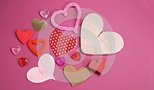 Many of craft valentine hearts shapes made from different materials on pink background with copy space