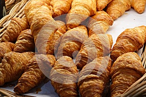 A Many croissants on on a black table in a bakery shop.