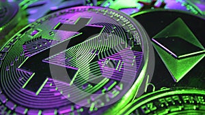 Many crypto money lie one over another in green and purple light. Coins rotate on the surface. Etherium, Bitcoin, ZCASH