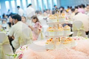 Many cupcakes on shelf shelves in wedding party. dessert serving for wedding guest. sweets mini cakes.