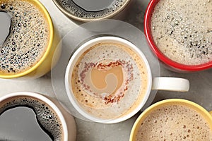 Many cups with different aromatic coffee on grey table, flat lay