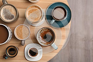 Many cups of different aromatic hot coffee on table