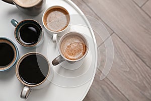 Many cups of different aromatic hot coffee on table