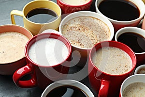 Many cups of different coffees on grey table, closeup