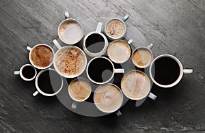 Many cups of different coffees on slate table, flat lay photo