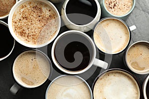 Many cups of different coffees on slate table, flat lay