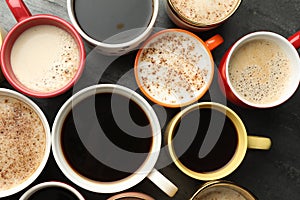 Many cups of different coffees on slate table, flat lay