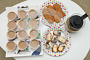 Many cups of hot tea with biscuits and cakes