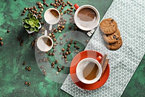 Many cups with tasty aromatic coffee and cookies on color table