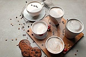 Many cups with tasty aromatic coffee and cookies on grey table