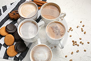 Many cups with tasty aromatic coffee and cookies on white table