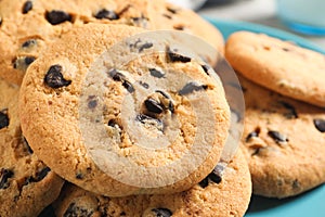 Many delicious chocolate chip cookies on plate, closeup