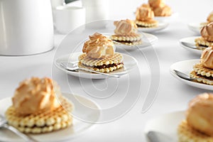 Many delicious waffles with cream served on white table for coffee break