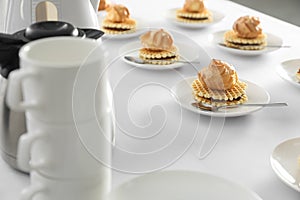 Many delicious waffles with cream served on white table for coffee break