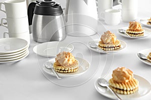 Many delicious waffles with cream served on white table for coffee break