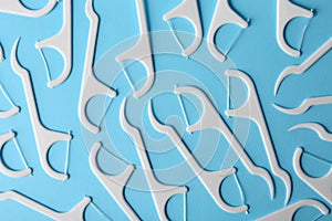 Many dental floss picks on color background, top view.
