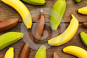 Many different bananas on wooden table, flat lay