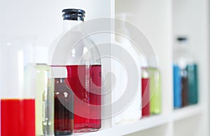 Many different bottles and test tubes with liquids of different colors stand on the shelf. Pharmacy.