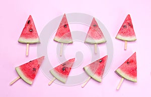 Many different bright ripe slices of watermelon on a stick on a bright pink background.