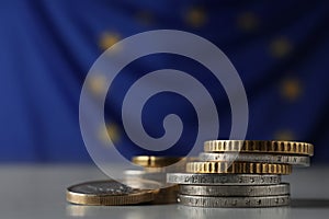 Many different coins on table against European Union flag, closeup. Space for text