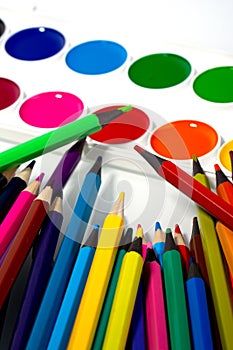 Many different colored pencils with watercolors on a white background. Multi-colored paint