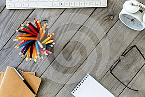 Many different colored pencils on wooden desktop