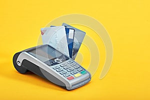 Many different credit cards and payment terminal on yellow background, closeup photo