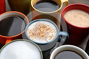 Many different cups with aromatic hot coffee on table, closeup