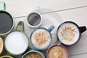 Many different cups with aromatic hot coffee on white table, flat lay