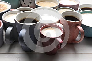 Many different cups with aromatic hot coffee on white wooden table