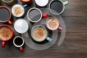 Many different cups with aromatic hot coffee on wooden table, flat lay