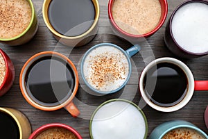 Many different cups with aromatic hot coffee on wooden table, flat lay