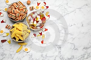 Many different delicious gummy candies on white marble table, flat lay. Space for text