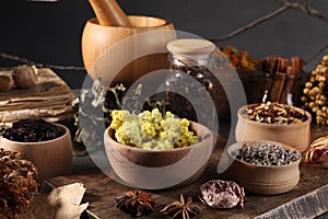 Many different dry herbs, flowers and mortar with pestle on table