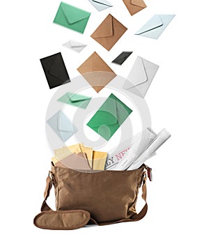 Many different envelopes falling into brown postman`s bag on white background