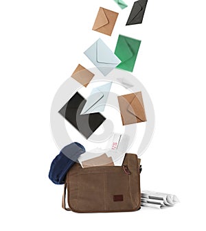 Many different envelopes falling into brown postman`s bag on white background